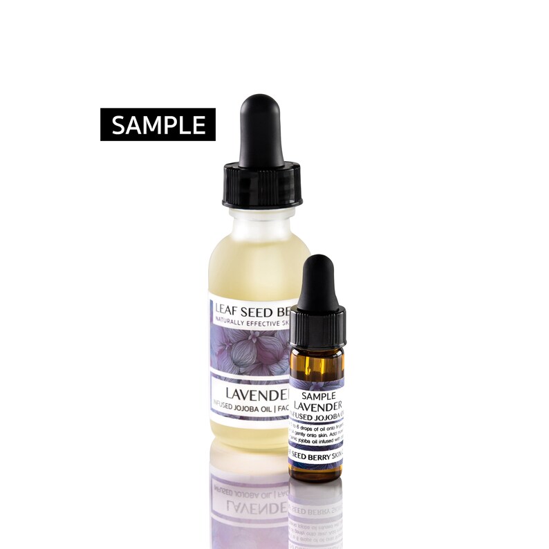 May include: Two glass bottles with dropper tops, one larger and one smaller. The larger bottle is clear and contains a light yellow liquid. The smaller bottle is amber colored and contains a darker liquid. Both bottles have labels with the text "LEAF SEED BE" and "LAVENDER USED JOJOBA OIL FAC". The smaller bottle also has the text "SAMPLE LAVENDER USED JOJOBA OIL" and "SEED BERRY SKIN".
