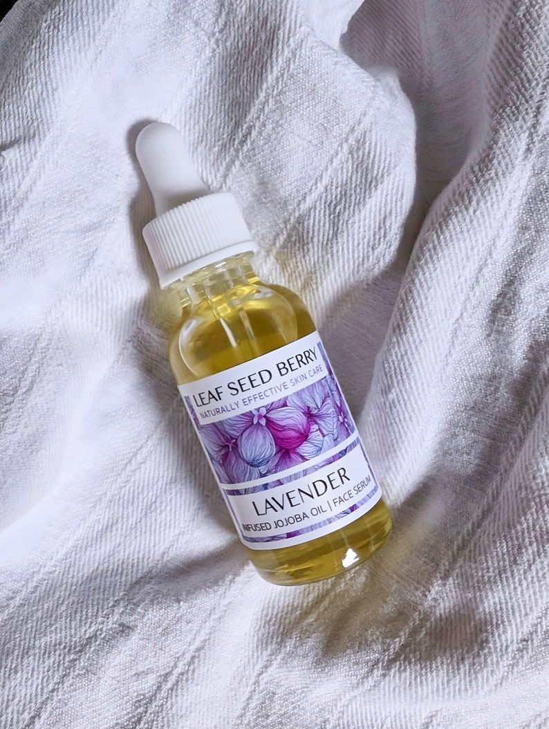 May include: A clear glass bottle with a dropper top filled with a yellow liquid. The bottle is labeled "LEAF SEED BERRY NATURALLY EFFECTIVE SKIN CARE LAVENDER INFUSED JOJOBA OIL | FACE SERUM".