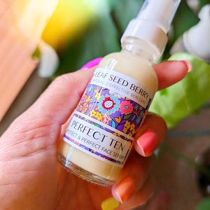 May include: A clear glass bottle with a white pump top and a colorful label that reads "Leaf Seed Berry Naturally Effective Skin Care Perfect Ten Protect & Perfect Face Serum".