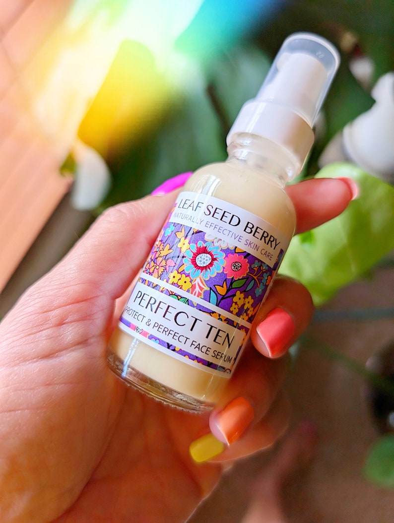 May include: A clear glass bottle with a white pump top and a colorful label that reads "Leaf Seed Berry Naturally Effective Skin Care Perfect Ten Protect & Perfect Face Serum".