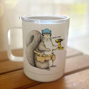 May include: White stainless steel travel mug with a blue hard hat wearing squirrel holding a drill and a tool belt. The squirrel is gray and has a black nose and eyes. The text on the mug says "Ahh nuts!"