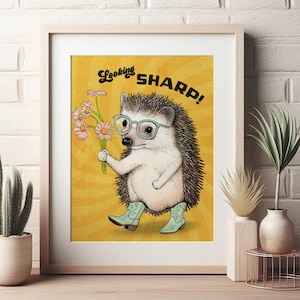 Peut inclure: Une illustration de dessin animé d'un hérisson portant des lunettes et des bottes de cow-boy, tenant un bouquet de fleurs roses et blanches. Le texte "Looking Sharp!" est écrit dans une police rétro au-dessus du hérisson.