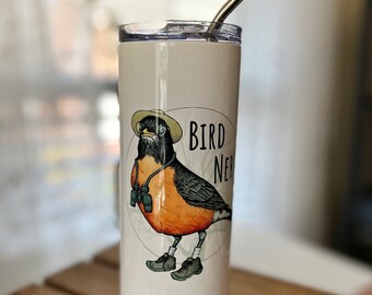 Puede incluir: Un vaso de acero inoxidable blanco con un gráfico de un pájaro que lleva un sombrero y binoculares. El texto "Bird Nerd" está impreso en el vaso.