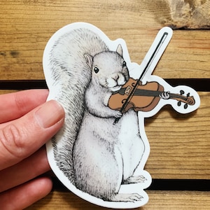 May include: A white squirrel playing a violin. The squirrel is holding the violin with its front paws and the bow with its back paw. The violin is brown with a light brown bow.