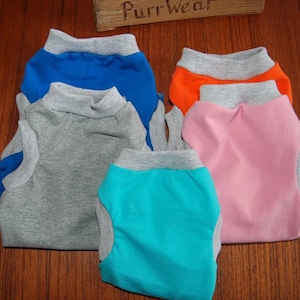 May include: Five sleeveless dog shirts in different colors. The shirts are stacked on top of each other. The colors are gray, blue, orange, pink, and turquoise.
