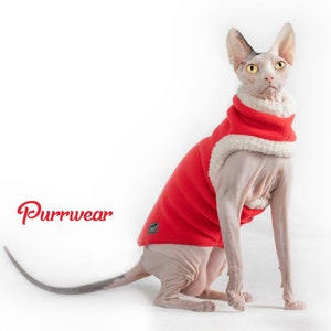 May include: A hairless cat wearing a red and white hooded sweater with the word "Purrwear" printed on the white background. The cat is sitting on a white surface.