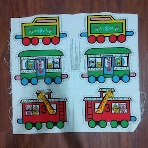 May include: A set of six fabric train car applique patterns. The patterns are for a yellow engine, a green passenger car, and four red box cars. Each car has a different animal on it. The patterns are printed on white fabric.