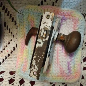 May include: A vintage door knob and latch set with a white painted finish and a brass knob. The knob has a round shape and a decorative design. The latch is rectangular and has a small lever handle.