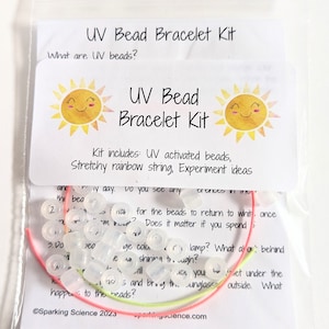 May include: A clear plastic bag containing a UV bead bracelet kit. The kit includes UV activated beads, stretchy rainbow string, and instructions for experimenting with the beads. The bag has a white card with the text "UV Bead Bracelet Kit" and two yellow suns with smiling faces.