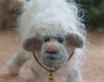May include: A white fluffy sheep toy with a brown leather collar and a gold bell. The sheep is standing on a wooden surface.
