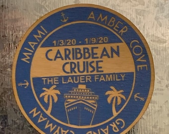 Könnte beinhalten: Ein rundes Holzsouvenir mit blauem Rand und hellbraunem Zentrum. Der Text lautet "Miami, Amber Cove, Grand Cayman, Caribbean Cruise, 1/3/20 - 1/9/20, The Lauer Family." Enthält ein Kreuzfahrtschiff, Anker und Palmen.