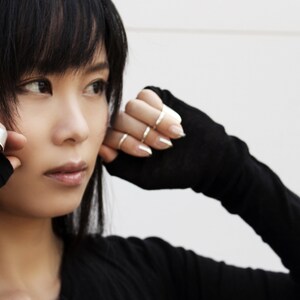 May include: A woman wearing black fingerless gloves with silver rings on her fingers. She is wearing a black long-sleeved shirt.