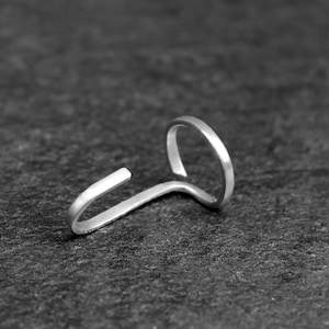 May include: A silver nose ring with a simple, curved design. The ring is made of metal and has a smooth finish.