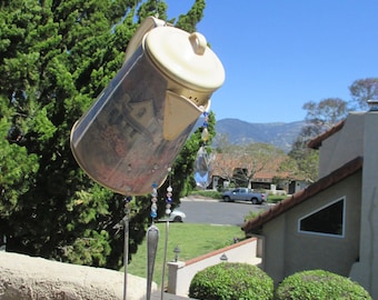 May include: A vintage-style coffee pot wind chime with a floral pattern and three silver spoons hanging from it. The wind chime is made of metal and has a beaded chain with colorful beads.