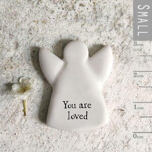 Può includere: Figurina di angelo in ceramica bianca con le parole "You are loved" incise sul davanti. La figurina è alta circa 3 cm.