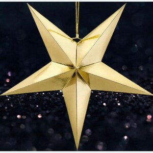 May include: A gold paper star ornament with a hanging loop. The star is 3-dimensional and has a shiny, metallic finish.
