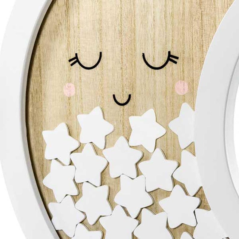 May include: A wooden moon-shaped wall decor with a smiling face and white star cutouts. The moon has a light wood grain background, black eyes and mouth, and pink cheeks. The frame is white.