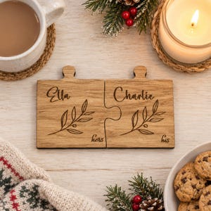 Puede incluir: Dos posavasos cuadrados de madera entrelazados con ramas botánicas grabadas y los nombres Ella y Charlie. El posavasos izquierdo está etiquetado como hers y el derecho como his, con un diseño de pieza de rompecabezas que los une.