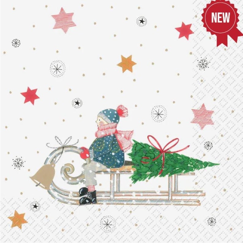 May include: A white paper napkin with a red, green, and blue illustration of a person on a sled pulling a Christmas tree. The background is white with gold and red stars.