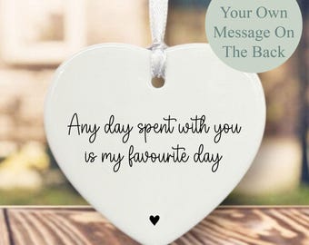 May include: White heart-shaped ceramic ornament with a silver ribbon for hanging. The front features the text "Any day spent with you is my favourite day" in black script, with a small black heart below. The back says "Add Your Own Message On The Back".