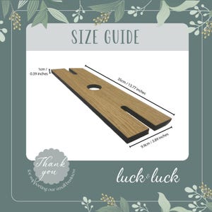 May include: Wooden wine glass holder with a light brown finish and black edges. The holder has a circular hole and two slots. Dimensions are 35cm/13.77 inches long and 9.9cm/3.89 inches wide. The text "SIZE GUIDE" is visible.