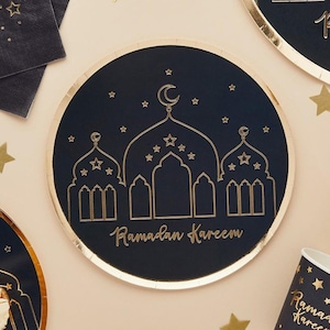Op de afbeelding: Een blauw papieren bord met een gouden folie rand heeft een gouden silhouet van een moskee met sterren en een halve maan. De tekst "Ramadan Kareem" is geschreven in gouden schrift.