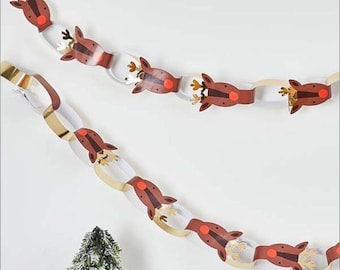 May include: A paper chain garland with reindeer heads in brown and red with gold accents. The garland is hanging on a white wall.