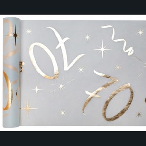 May include: A roll of light blue wrapping paper with a gold foil design. The design features the words "Happy" and "New Year" in a stylised script font, along with stars and confetti.