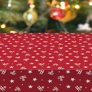 May include: A red Christmas tablecloth with a repeating pattern of white stars and the word "Ho" with a small airplane design. The tablecloth is in front of a blurred Christmas tree with ornaments.