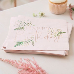 K&ouml;nnte beinhalten: Ein Stapel rosa Papierservietten mit einem floralen Design und dem Text "Happy Birthday" in goldener Folie.