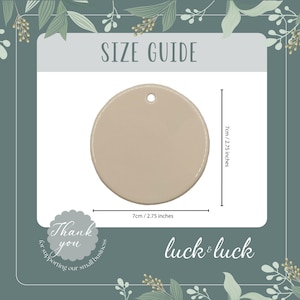Op de afbeelding: Een beige cirkelvormig ornament met een klein gaatje aan de bovenkant om op te hangen. De maattabel geeft een diameter van 7 cm aan. De afbeelding bevat de tekst SIZE GUIDE, Thank you for supporting our small business en luck & luck.