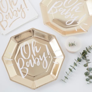 May include: Gold paper plates with a white "Oh Baby!" inscription. The plates are octagonal and have a metallic sheen.