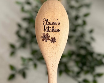 May include: A wooden spoon with the text "Elaine's Kitchen" engraved on it. Two small flower designs are also engraved on the spoon.