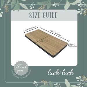 Puede incluir: Un rompecabezas de madera con dos piezas, que mide 20 cm por 10 cm. El rompecabezas est&aacute; hecho de madera marr&oacute;n claro con un borde negro. El texto "luck & luck" est&aacute; impreso en la parte inferior de la imagen.