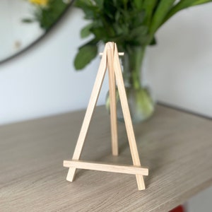 May include: A small wooden easel, perfect for displaying small artwork or photos. The easel is made of natural wood and has a simple, classic design.
