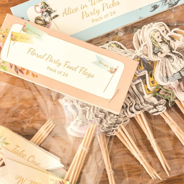 Peut inclure: Un ensemble de 24 drapeaux alimentaires pour fête sur le thème d'Alice au pays des merveilles. Les drapeaux présentent des illustrations d'Alice, du Chapelier fou, de la Reine de cœur et d'autres personnages du livre. Les drapeaux sont imprimés sur du papier cartonné blanc et ont une finition pailletée dorée. Les drapeaux sont fixés à des brochettes en bois.