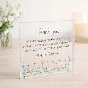 May include: A clear rectangular acrylic block featuring black printed text that reads: Thank you FOR THE amazing PERSON YOU ARE. FOR ALL THAT YOU DO AND THE difference YOU MAKE. YOU ARE TRULY appreciated lots of love Sandra xxx, with floral art.