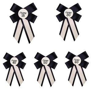 May include: Five decorative ribbon bows in black and white satin. Each bow features a central circular white badge with black text reading Happy 18, Happy 30, Happy 40, Happy 50, and Happy 60. The bows have two long, downward-hanging tails.