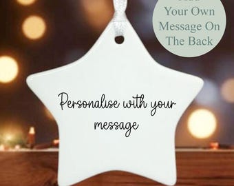 May include: A white star-shaped ornament with a ribbon for hanging. The front of the ornament has the text "Personalise with your message" in cursive script. A circular graphic on the right says "Add Your Own Message On The Back".