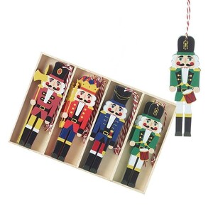 May include: A set of five flat wooden nutcracker ornaments in a rectangular box. Four ornaments are arranged inside the box, and one is suspended outside. Each nutcracker features a painted uniform, a black hat, and a red and white hanging string.