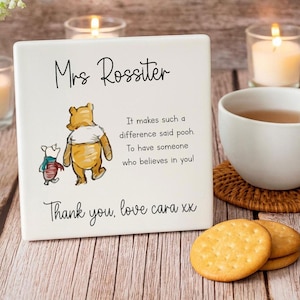 Könnte beinhalten: Eine weiße Keramikfliese mit einer Winnie-the-Pooh-Illustration und Text. Der Text lautet "Mrs Rossiter", "It makes such a difference said pooh. To have someone who believes in you!" und "Thank you, love cara xx".