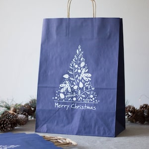 Könnte beinhalten: Eine blaue Papiertüte mit einem weißen Design eines stilisierten Weihnachtsbaums und dem Text "Merry Christmas".