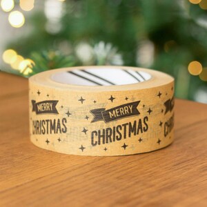 May include: A roll of brown packing tape with the words "Merry Christmas" printed on it in black. The tape is decorated with small black stars.