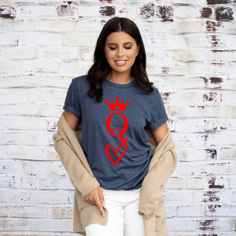 May include: A navy blue t-shirt with a red graphic of a queen of hearts playing card with a crown on top.