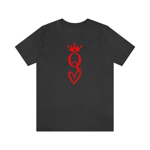 May include: A dark heather grey t-shirt with a red graphic of a queen of hearts playing card. The queen is wearing a crown and holding a heart.
