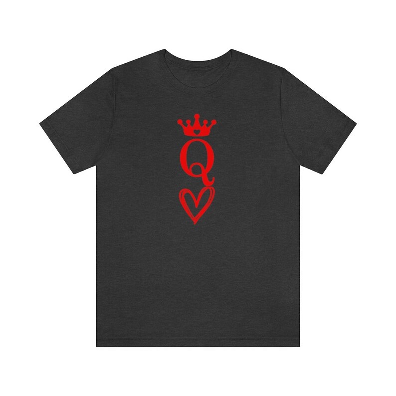 May include: A dark heather grey t-shirt with a red graphic of a queen of hearts playing card. The queen is wearing a crown and holding a heart.
