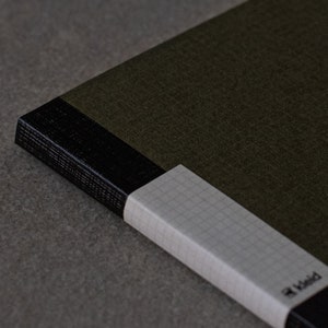 May include: A green notebook with a black spine and a white gridded page edge. The notebook has the word "Field" printed on the edge.