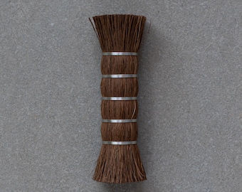 May include: A brown brush with a natural bristle head and a wooden handle. The handle is wrapped with silver metal bands.