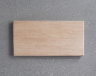 May include: A rectangular wooden board with a light brown finish, showcasing the natural wood grain. The board is positioned horizontally against a gray background, providing a neutral backdrop for the product.