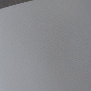 May include: A blank, white, gridded notebook with a light gray background.